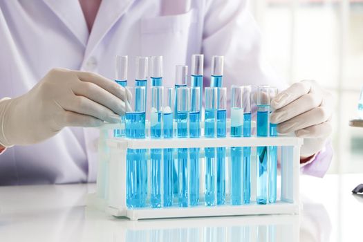 An Asian scientist or chemist drops a blue liquid chemical in a laboratory. Research concepts in healthcare, pharmacy, and medicine. Liquid analysis to separate DNA and molecules in vitro.