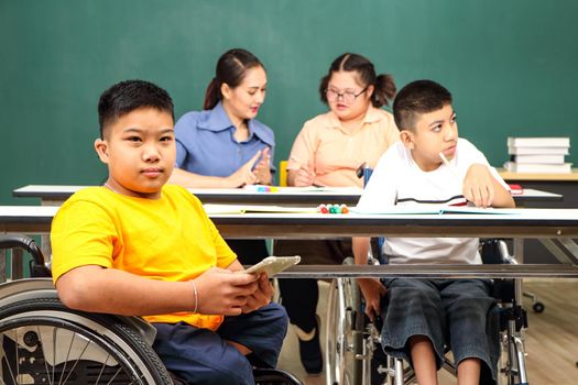 Asian disabled children Or, an autistic child learns to read, write, and train their hand and finger muscles with a teacher at their classroom desk. Concentrate and smile Happy disability kid concept