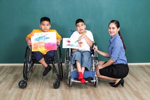 A group of young girls with disabilities and autism is training their hand and finger muscles by drawing and painting with water. With the help of teachers Happy and focused in the classroom