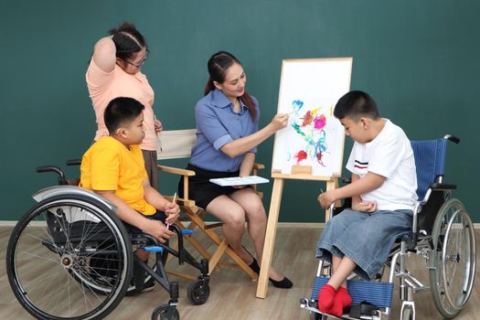 A group of young girls with disabilities and autism is training their hand and finger muscles by drawing and painting with water. With the help of teachers Happy and focused in the classroom