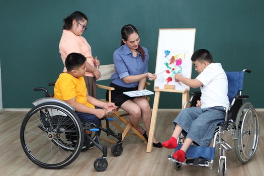 A group of young girls with disabilities and autism is training their hand and finger muscles by drawing and painting with water. With the help of teachers Happy and focused in the classroom