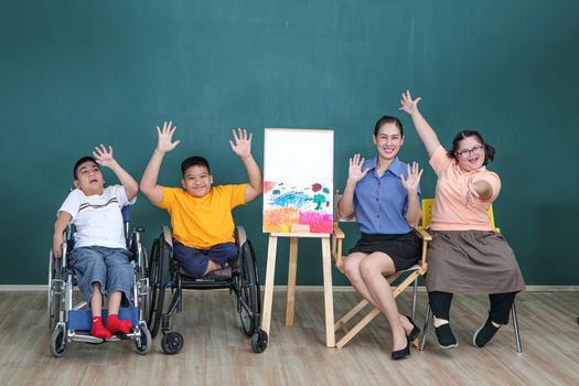 A group of young girls with disabilities and autism is training their hand and finger muscles by drawing and painting with water. With the help of teachers Happy and focused in the classroom