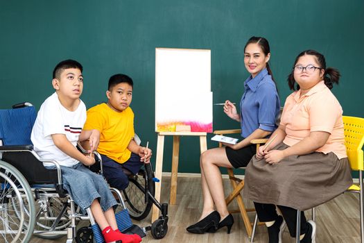 A group of young girls with disabilities and autism is training their hand and finger muscles by drawing and painting with water. With the help of teachers Happy and focused in the classroom