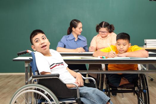 Asian disabled children Or, an autistic child learns to read, write, and train their hand and finger muscles with a teacher at their classroom desk. Concentrate and smile Happy disability kid concept