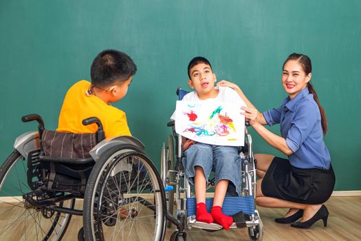 A group of young girls with disabilities and autism is training their hand and finger muscles by drawing and painting with water. With the help of teachers Happy and focused in the classroom