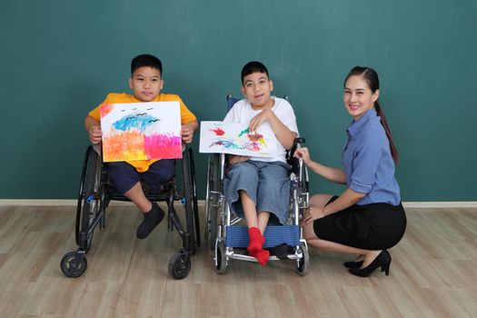 A group of young girls with disabilities and autism is training their hand and finger muscles by drawing and painting with water. With the help of teachers Happy and focused in the classroom