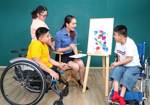 A group of young girls with disabilities and autism is training their hand and finger muscles by drawing and painting with water. With the help of teachers Happy and focused in the classroom