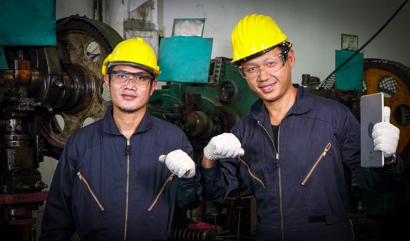 Two Asian male workers in a Yunifom uniform. Wear a safety hat and wear gloves. Hand-collision greeting concept teamwork Smiling staff, helping others, the mood of teamwork. In industrial plants