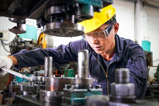 Asian technician Wear uniform Helmet with wrench In machine inspection, the concept of machine control, maintenance and check the operation of machines Working in industrial and manufacturing plants