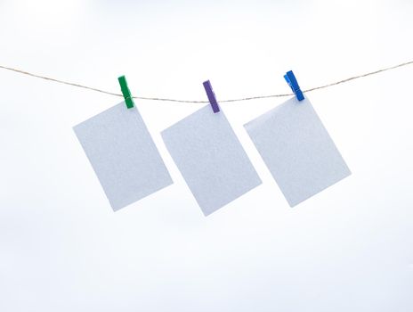 Empty paper sheets for notes, frames that hang on a rope with clothespins, collection of various notes, Mockup template for memories, and a clothes pegs on white background. Blank cards on the rope.