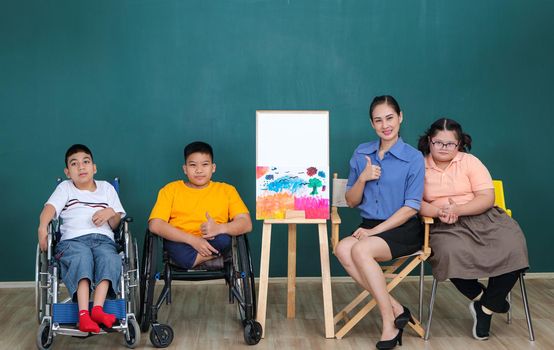 A group of young girls with disabilities and autism is training their hand and finger muscles by drawing and painting with water. With the help of teachers Happy and focused in the classroom