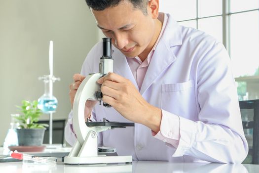 Asian scientists or chemists use a microscope. In science experiment Medical pharmaceutical research concept DNA structure, innovation and technology