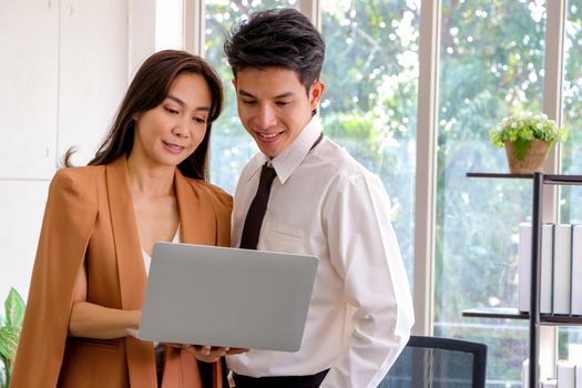 Asian businessmen and women stand and hold laptop looked relaxed, smiling from work. Work plan, brainstorm, strategy Creative Lifestyle, Success in Business Concept