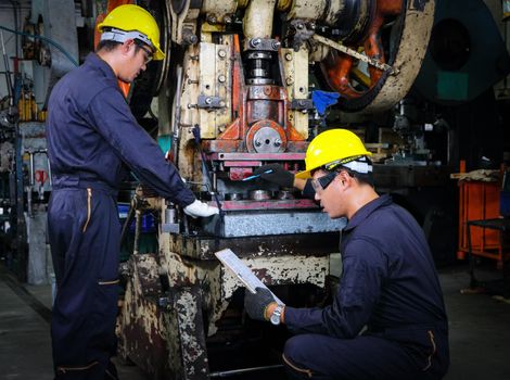 Asian male worker In industries that wear glasses, safety hats and safety uniforms Wrench tool holder stand Machine maintenance technician operation concept In an industrial factory with confidence