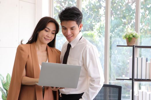 Asian businessmen and women stand and hold laptop looked relaxed, smiling from work. Work plan, brainstorm, strategy Creative Lifestyle, Success in Business Concept