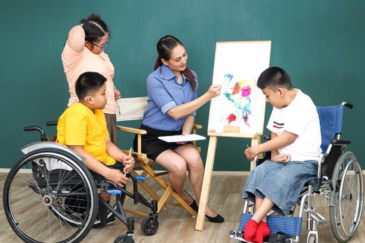 A group of young girls with disabilities and autism is training their hand and finger muscles by drawing and painting with water. With the help of teachers Happy and focused in the classroom