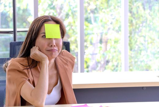 Asian businesswomen look and write a post-it note on their faces to relax and smile from work. Work plan, brainstorm, strategy Creative Lifestyle, Success in Business Concept