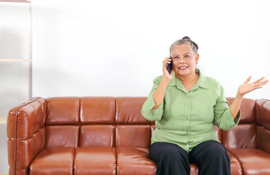 Asian women Retirement Use a smartphone and laptop in the living room concept to work at home. Quarantine to prevent spreading disease Or a conversation with someone far away Via the Internet