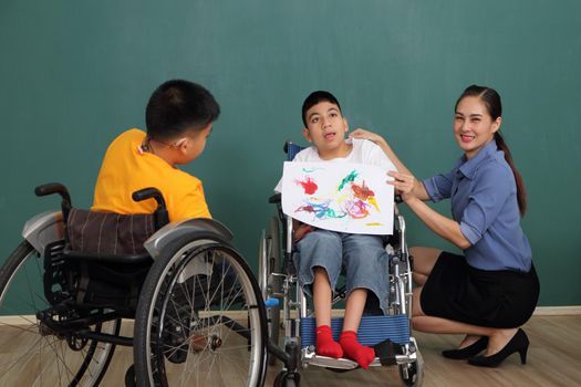 A group of young girls with disabilities and autism is training their hand and finger muscles by drawing and painting with water. With the help of teachers Happy and focused in the classroom