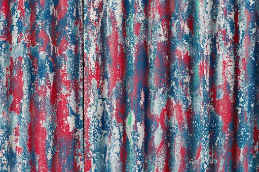colorful motley peeled off red and blue paint layers on corrugated zinc coated steel sheet - full frame background and texture