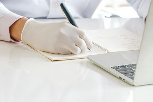 Asian researchers in white coats The concept of working in a scientific laboratory Using a laptop to find information And write down in the test results book Or making a report in a science laboratory