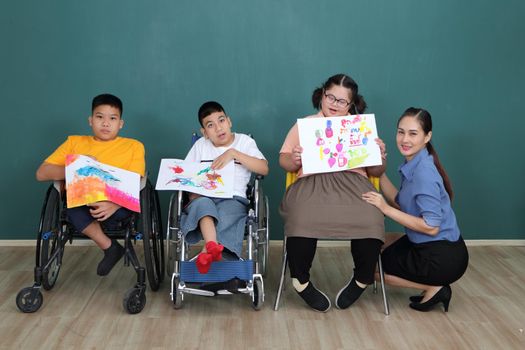 A group of young girls with disabilities and autism is training their hand and finger muscles by drawing and painting with water. With the help of teachers Happy and focused in the classroom