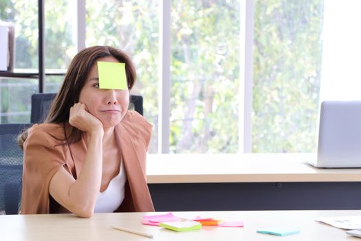 Asian businesswomen look and write a post-it note on their faces to relax and smile from work. Work plan, brainstorm, strategy Creative Lifestyle, Success in Business Concept
