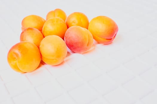 A juicy, soft fruit, resembling a small peach, of an orange-yellow color.Fresh ripe apricot fruits isolated on white ribbed background. High quality photo