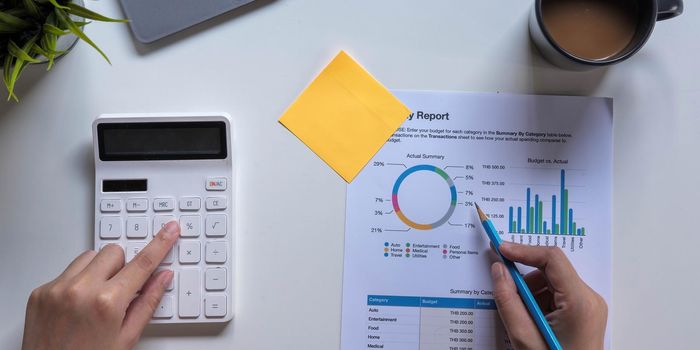 Woman with financial report and calculator. Woman using calculator to calculate report at the table in office.