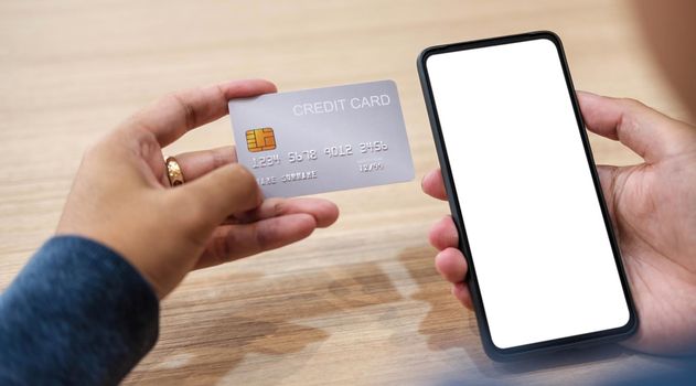 Close up hand of woman shopping online with credit card using smart phone at cafe.