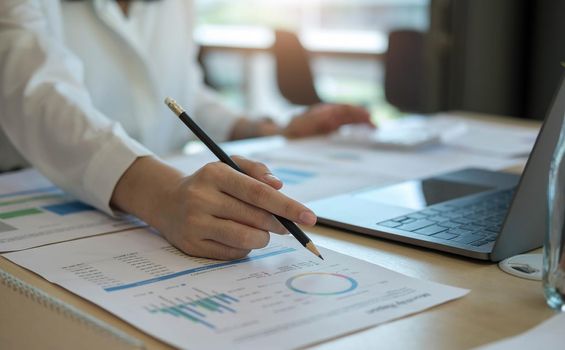 Close up Businesswoman using calculator and laptop for calaulating finance, tax, accounting, statistics and analytic research concept.