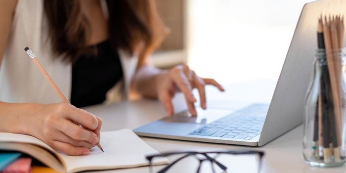 Close up Businesswoman hand holding pen and pointing at financial paperwork, financial charts to analyze profit concept.