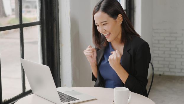 Yes! Happy excited successful, Asian businesswoman smile workstation triumphing with raised hands with laptop computer, woman success project online winner