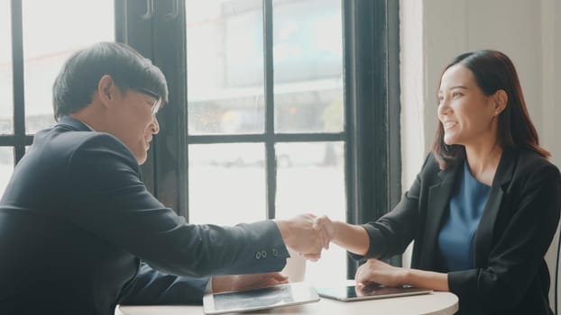 Happy two young businessman and woman shaking hands after successful meeting or negotiation with digital tablet sitting on desk cafe, Businesspeople discussion and smile lunch