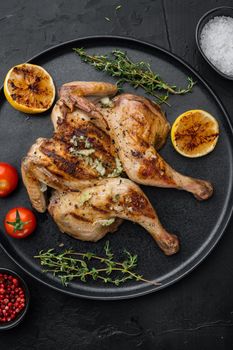 Freshly cooked rotisserie chicken with herbs, on black background, top view