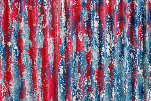 colorful motley peeled off red and blue paint layers on corrugated zinc coated steel sheet - full frame background and texture