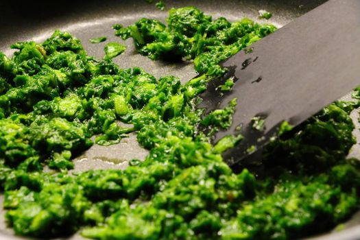 Cooking spinach in a skillet at home. Light dinner