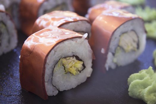 Assorted sushi food on a black slate plate. No people