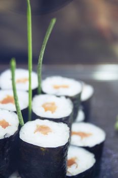 Assorted sushi food on a black slate plate. No people