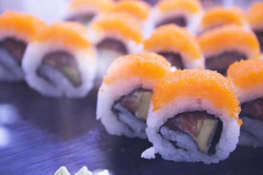 Assorted sushi food on a black slate plate. No people