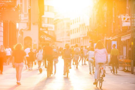 Blurred crowd of people on Copova pedestrian street in Ljubljana at sunset. Urban lifestyle and mobility concept