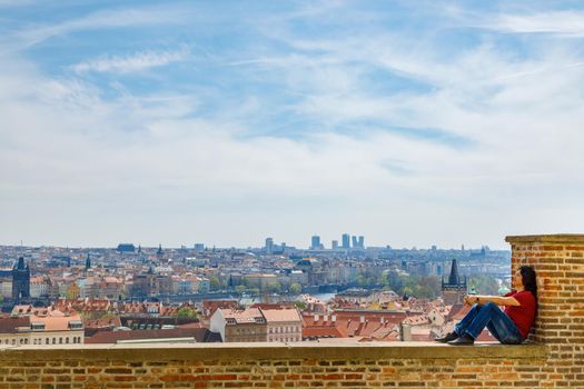 A man sits on a brick wall and admires the panorama of Prague. Travel