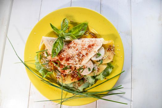 Vegan cuisine presentation of a flatbread based on entirely vegetable foods prepared on a mustard-colored plate 