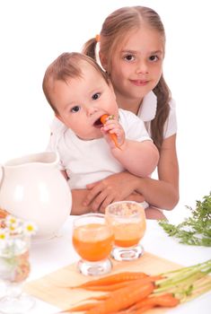 Nice blond baby girl with glass of carrot juice