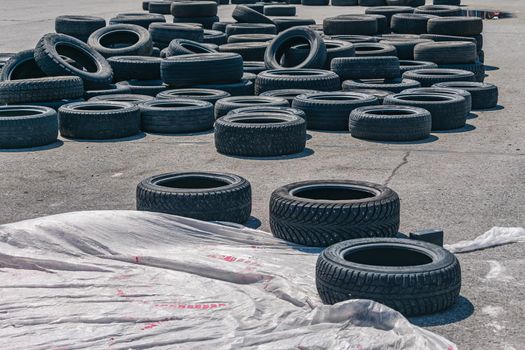 Lots of old car tires piled up on the race track. Car tires assembled to create safety fencing on the race track