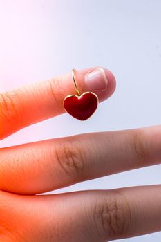 Red color heart shape earring in hand on white