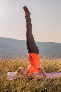 Beautiful woman doing yoga in the nature,Salamba Sarvangasana/Supported Shoulderstand.Image is intentionally toned.