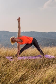 Beautiful woman doing yoga in the nature,Trikonasana/Triangle pose.Image is intentionally toned.