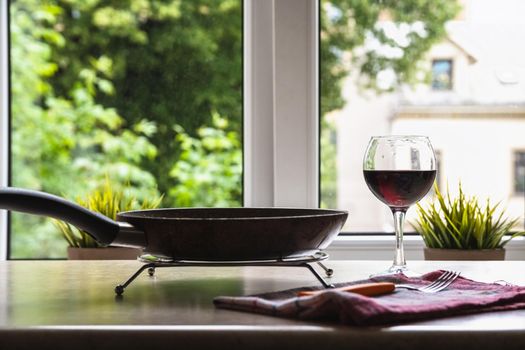 Barchelor breakfast - fried eggs with sausages on a teflon frying pan with glass of red wine