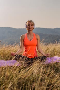Beautiful woman sitting in lotus position with headphones and meditating in the nature,Padmasana/Lotus position.Image is intentionally toned.